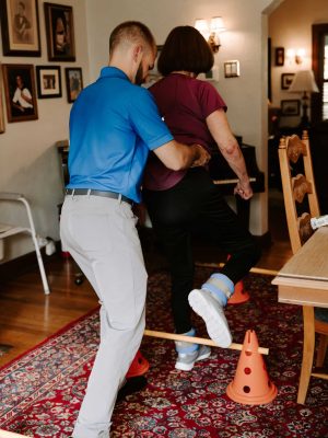 Physiotherapy At Home - Dr Charles helping patient walk over objects and practice balance